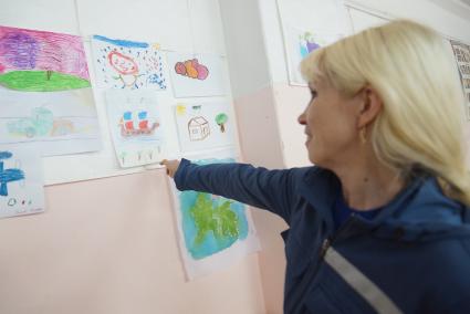 Сотрудница психологической службы МЧС показывает рисункок ребенка-беженца из Украины в пункте временного пребывания в Каменске-Уральском нарисовавшего корабль с парусами цветов Российского триколора