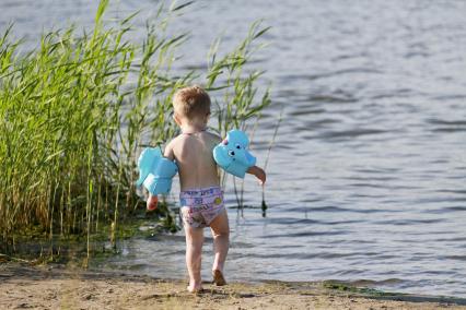 Ребенок на пляже в нарукавниках.