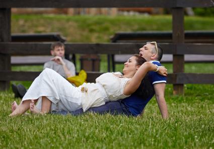 Мужчина и женщина отдыхают лежа на траве в парке.
