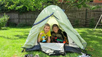 Дача. На снимке: мальчики сидят в палатке с фонариком и водным пистолетом.
