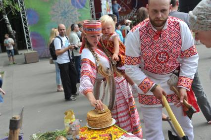 В парке `Кузьминки` отметили `День семьи, любви и верности`.  Реконструкция традиционного свадебного обряда, который существовал во времена Древней Руси. На снимке: мужчина и женщина с ребенком в русском национальном костюме.