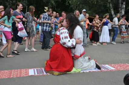 В парке `Кузьминки` отметили `День семьи, любви и верности`.  Реконструкция традиционного свадебного обряда, который существовал во времена Древней Руси. На снимке: мужчина и женщина целуются сидя на свадебном рушнике.