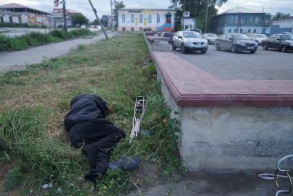 пьяный инвалид с костылями спит в траве в городе