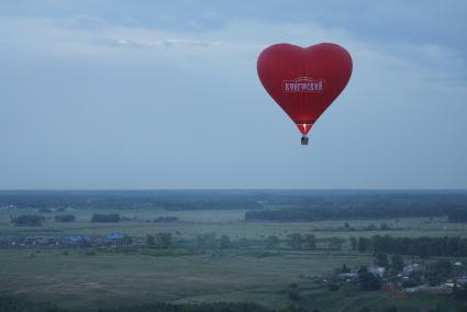 воздушный шар в форме сердца летит над землей во время фестиваля вздухоплавания\"небо на ладони\" в Каменске-Уральском\"