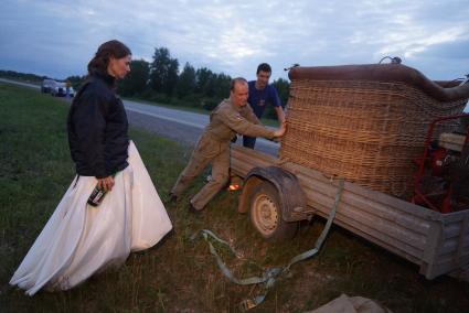 невеста с  шампанским в руке наблюдает за погрузкой корзины аэростата