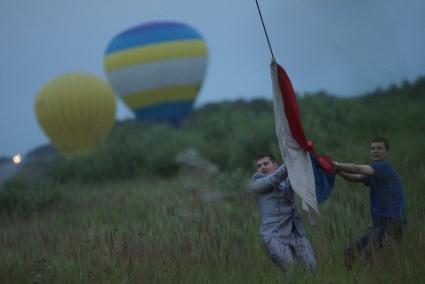 группа подбора и жених помогают пилоту сдуть шар после посадки на фестивале воздухоплавания небо на ладони в каменске-уральском