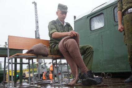 Солдат железнодорожных войск переодевается в утепленую одежду перед одеванием водолазного костюма