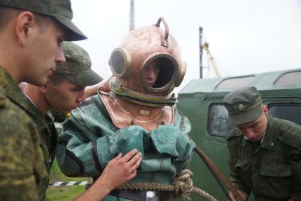 Солдат железнодорожных войск в водолазном костюме и тяжелом водолазном шлеме перед погружением