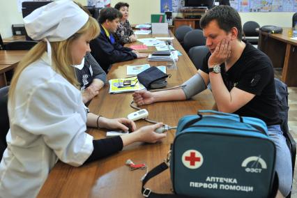 День открытых дверей в ГБУ `Жилищник` района Люблино. На снимке: медицинский работник измеряет мужчине давление.