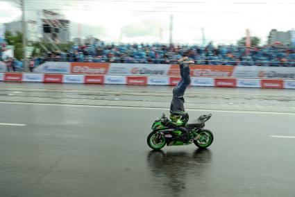 Мотоциклист выполняет трюк, едет на мотоцикле стоя на голове, во время автошоу в Екатеринбурге
