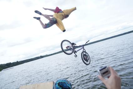 Прыжки на велосипедах в воду Bicycle live fest, парень в костюме банана прыгает на велосипеде с трамплина