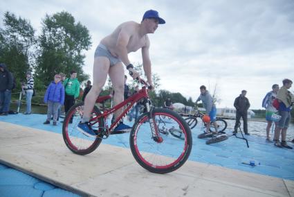 Прыжки на велосипедах в воду Bicycle live fest, парень в трусах едет к трамплину