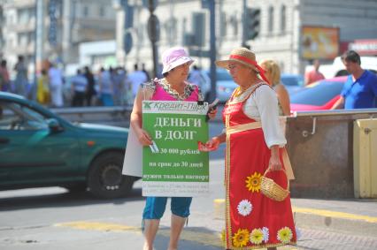 Женщины раздают рекламные листовки.