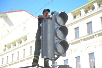 Мужчина ремонтирует светофор.