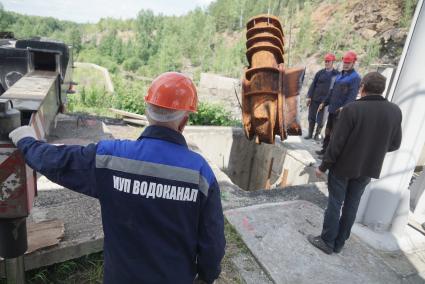 рабочие МУП Водоканал наблюдают за подьемом из шахты 4-тонной задвижки на плотине Волчихинского водохранилица в Свердловской области