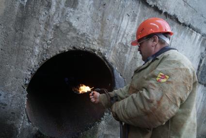 Сварщик поджигает газовую горелку перед тем как отрезать трубу 4-тонной задвижки на плотине Волчихинского водохранилище