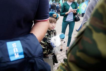 девочка держит на руках мальтийскую болонку с голубом берете во время празднования дня ВДВ в Екатеринбурге