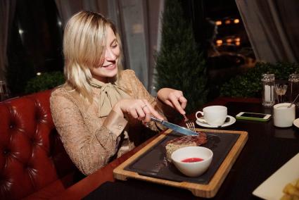 Девушка в ресторане  \"Огонек\" в Екатеринбурге, который ввел санкционное меню., ест отбивную из говяжей вырезки с перлотто и клюквеным соусом
