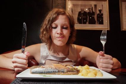 Девушка в ресторане  \"Огонек\" в Екатеринбурге, который ввел санкционное меню., ест блюдо \"скумбрия подкопченая и запеченая с ароматными дачными травами с отварным картофелем и сливочным маслом\"