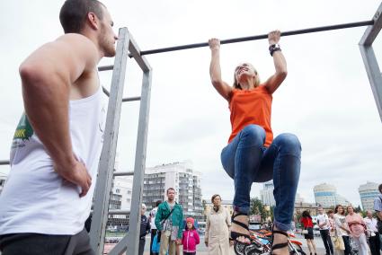 Девушка в день физкультурника подтягивается на перекладине