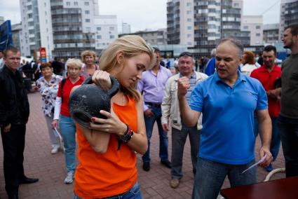 девушка в день физкультурника тягает гирю