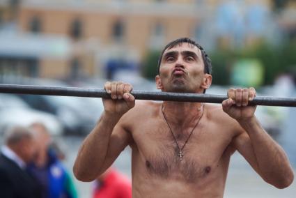 Мужчина в день физкультурника подтягивается на перекладине