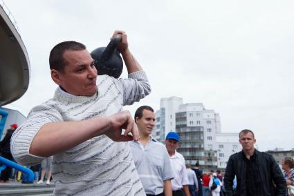 Мужчина в день физкультурника тягает гирю