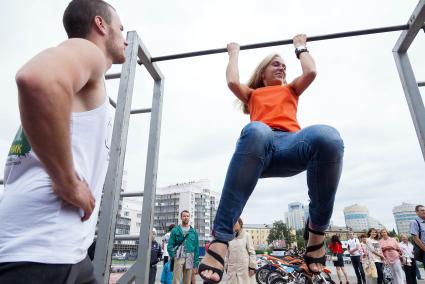 Девушка в день физкультурника подтягивается на перекладине