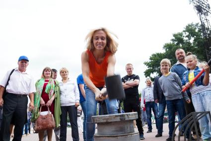 Девушка в день физкультурника бьет кувалдой по наковальне силомера