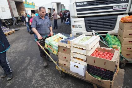 рабочий 4-й овощебазы в Екатеринбурге везет тележку с овощами и фруктами