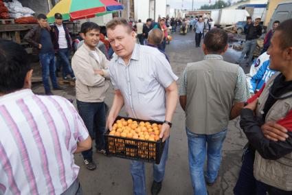 мужчина несет ящик с персиками на 4-й овощебазе в Екатеринбурге