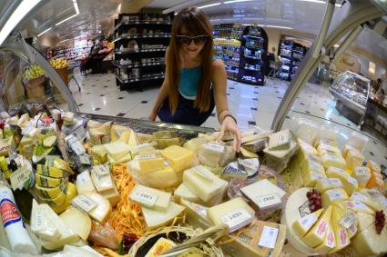 Магазин `Соседушка` в Оренбурге. На снимке: девушка выбирает сыр на витрине.