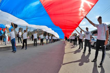 День государственного флага России в Новосибирске. Мужчину держат огромный российский флаг.