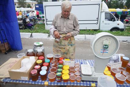 мужчина считает деньги после продажи меда на Ирбитской ярмарке