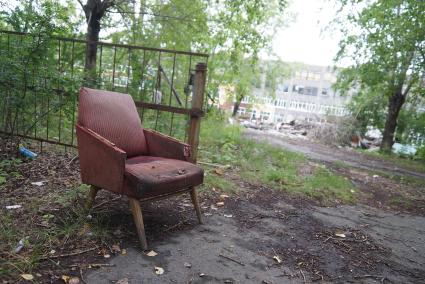 рваное кресло стоит у входа на территорию заброшеных цехов ирбитского мотоциклетного завода в городе Ирбит