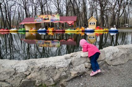 Ребенок у паркового пруда с водными аттракционами.