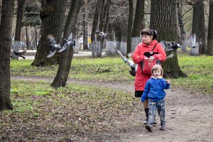 Ребенок с женщиной гуляют по весеннему парку.