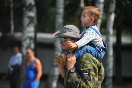 Учебный центр служебного собаководства в Дмитрове. Парад с участием 400 служебных собак, посвященный 90-ой годовщине образования. На снимке: мужчина несет ребенка на плечах.