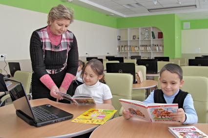 Читальный зал общеобразовательной школы. Дети читают книги.