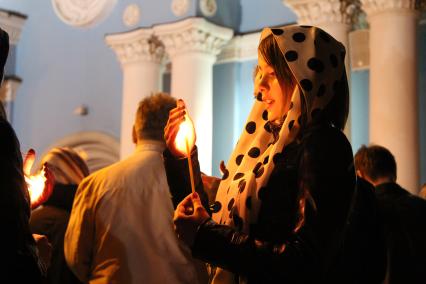 Девушка со свечой у храма перед началом пасхального богослужения.