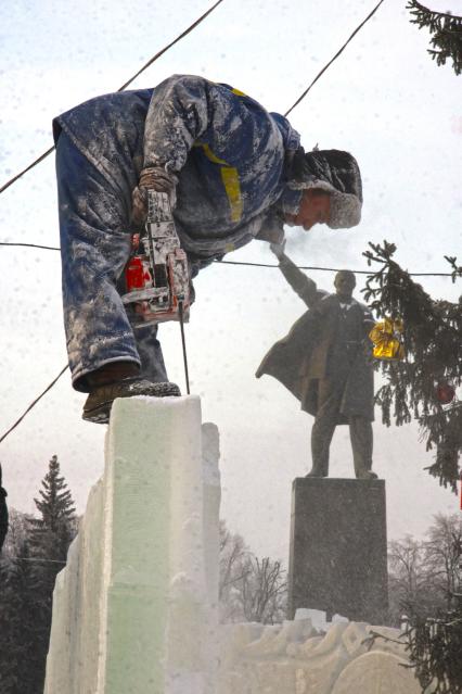 Строительство ледового городка в Уфе. Рабочий пилит лед напротив памятника В.И. Ленину.