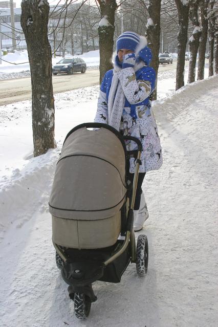 Девушка с детской коляской на морозе.