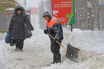 Снегопад. Женщина дворник чистит улицу от снега.