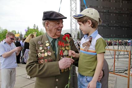 Мальчик дарит ветерану гвоздику.