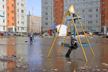 Дети играют на затопленной детской площадке.