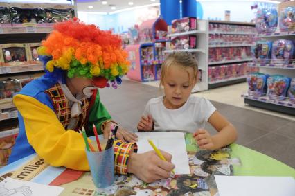 Открытие флагманского магазина `Детский мир` на Воздвиженке. На снимке: девочка с клоуном рисуют за столом.