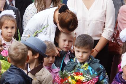 Мама целует сына в лоб во время школьной линейки 1 сентября.