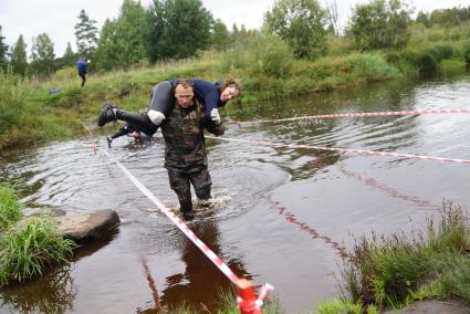 Участник грязных гонок Ural Dirty Race 2014 под Екатеринбургом  переходит речку в брод с напарницей на плечах