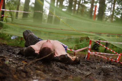 Участник грязных гонок Ural Dirty Race 2014 под Екатеринбургом  ползет на спине по грязи