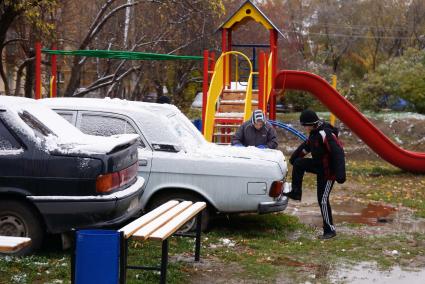 мальчики играют у старой машины Волга, на детской площадке во дворе жилого дома